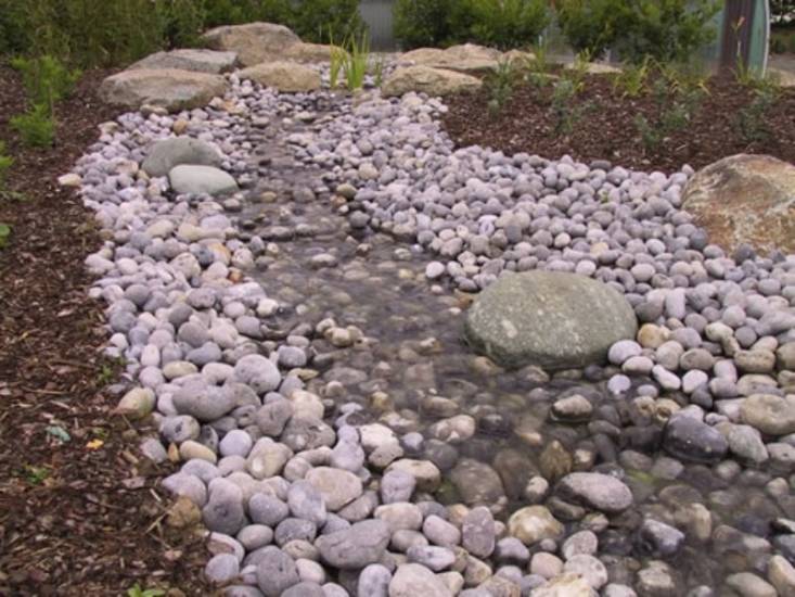 Réalisation d'un cours d'eau en pierres naturelles par l'équipe Les Jardins de Romain.
